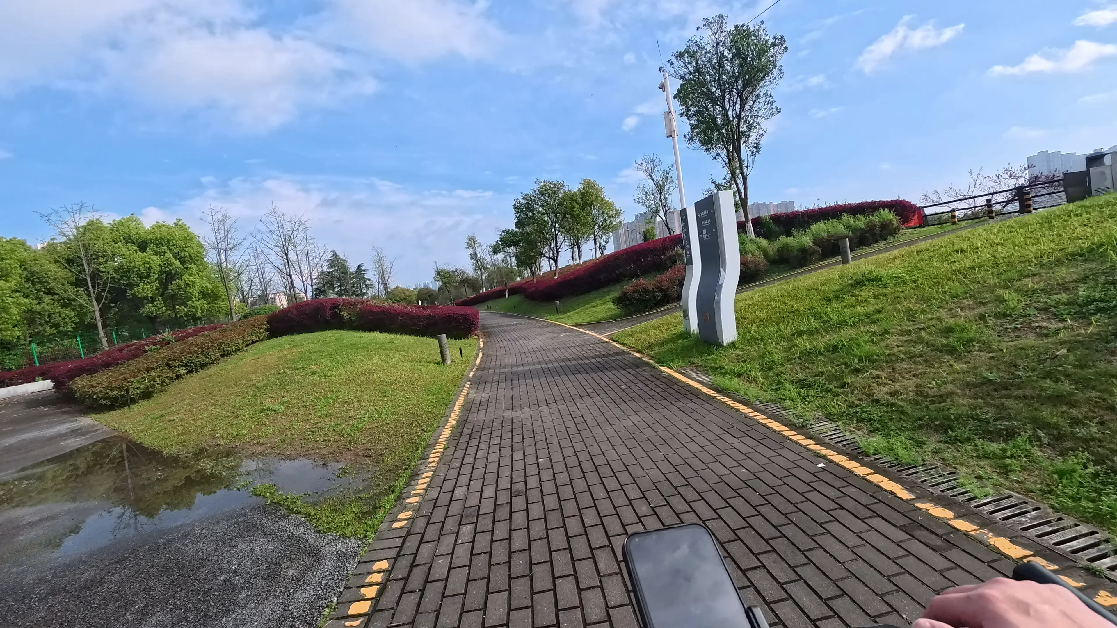 POV cycling along a peaceful riverside trail beneath a bright sky